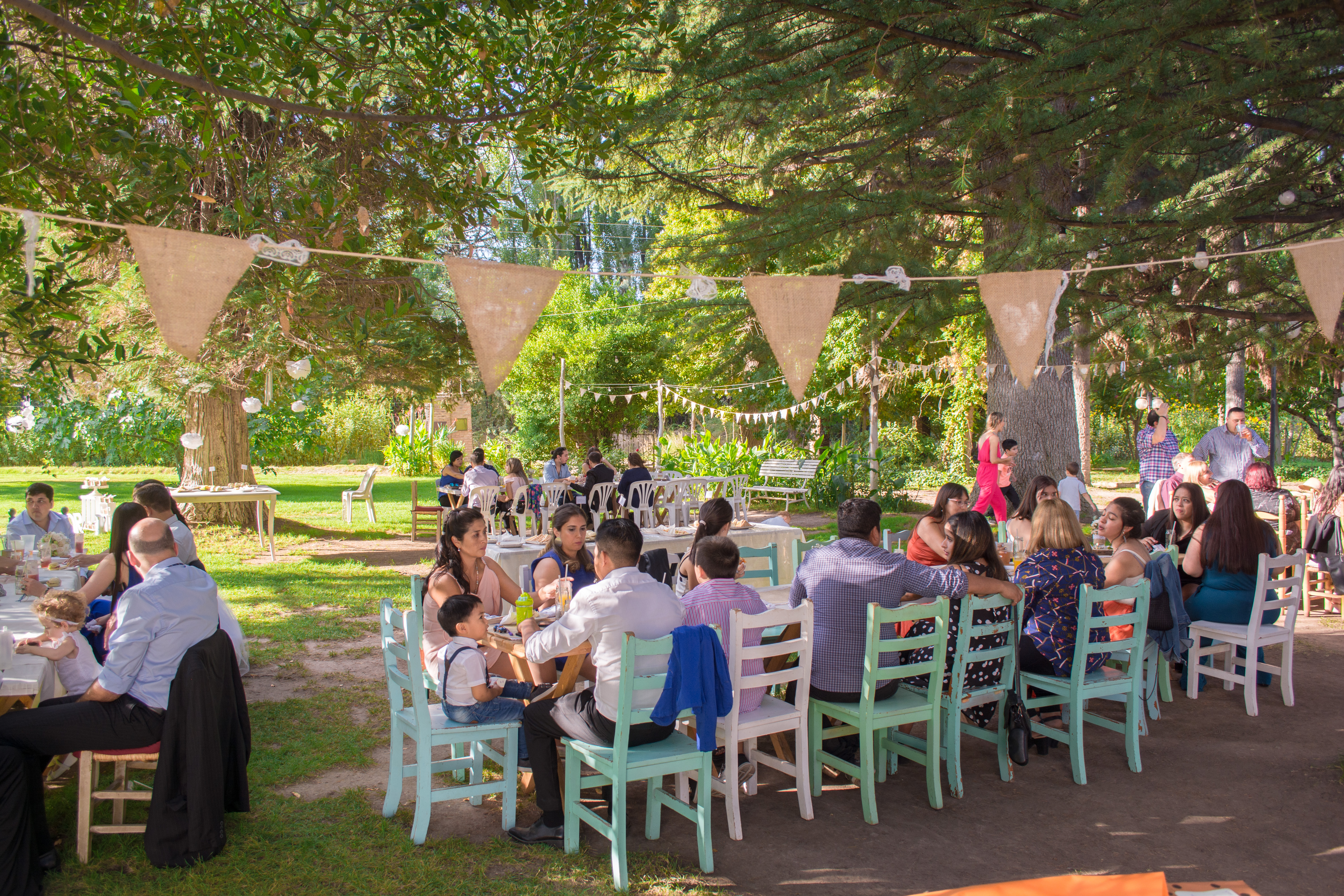 Foto de un casamiento con mesas juntas y gente pasando la tarde
